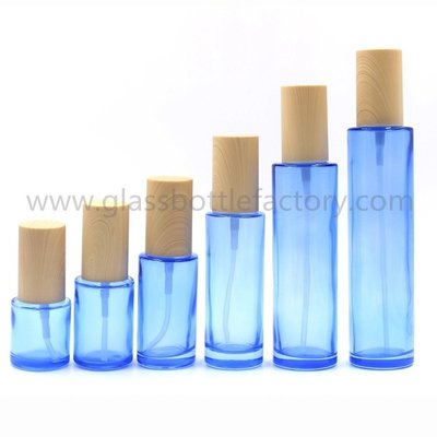 China New Model  20ml,30ml,40ml,60ml,80ml,100ml,120ml Blue Cylinder Glass Lotion Bottles With Pumps and Wood Caps supplier